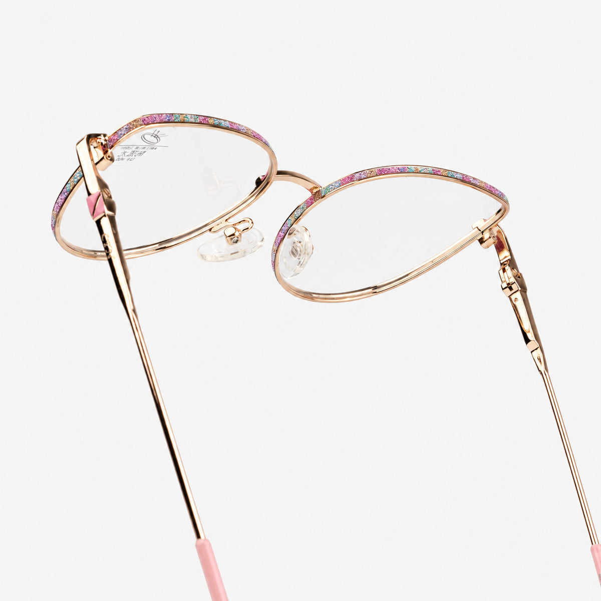 Detalle de plaquetas ajustables y ceja de glitter rosa en gafas con filtro azul Piclek