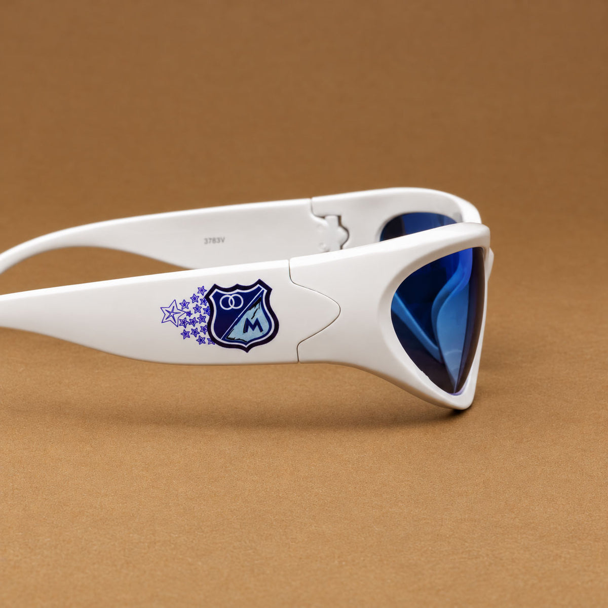 Detalle en primer plano del escudo azul de Millonarios FC con estrellas en varilla de gafa envolvente Piclek